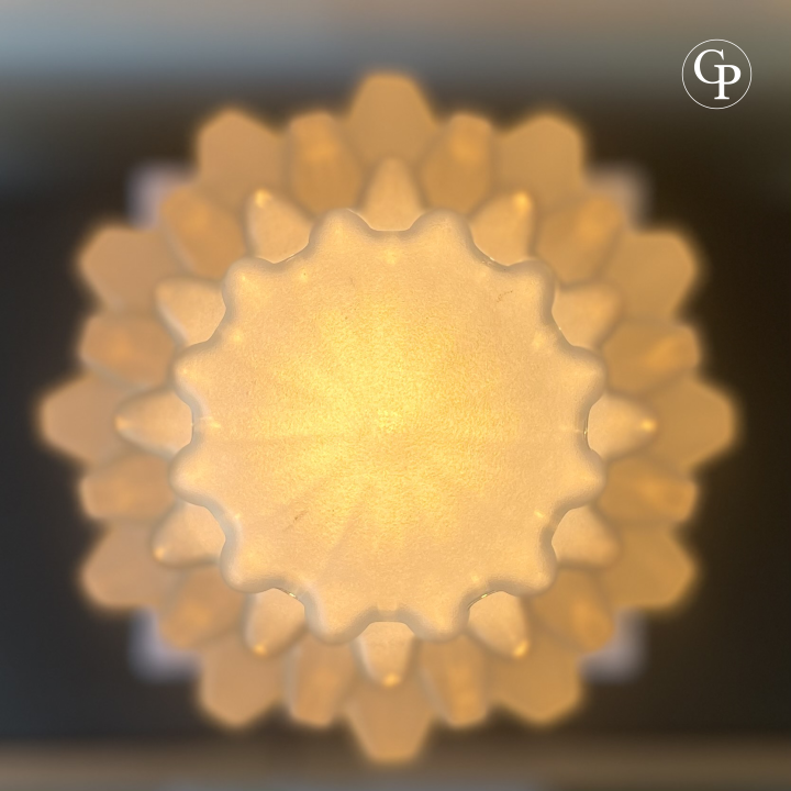 Overhead detail of illuminated Art Deco Skyscraper lamp showing sculpted frosted glass top and warm glowing geometric design | Détail en vue plongeante de la lampe Art Déco Skyscraper illuminée montrant le sommet en verre dépoli sculpté et son design géométrique lumineux