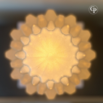 Overhead detail of illuminated Art Deco Skyscraper lamp showing sculpted frosted glass top and warm glowing geometric design | Détail en vue plongeante de la lampe Art Déco Skyscraper illuminée montrant le sommet en verre dépoli sculpté et son design géométrique lumineux