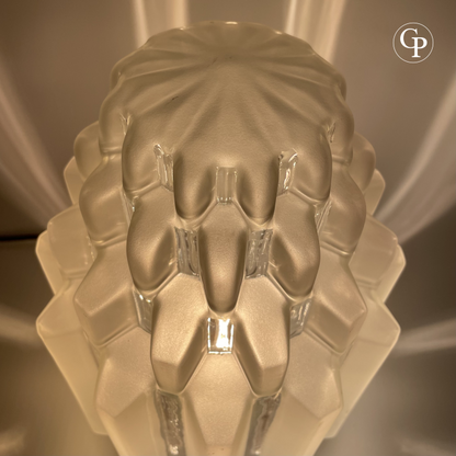 Close-up detail of the top of a vintage Art Deco table lamp showing the intricate geometric stepped pattern of the frosted glass shade | Gros plan détaillé du sommet d’une lampe de table vintage Art Déco mettant en valeur le motif géométrique à étages de l’abat-jour en verre dépoli
