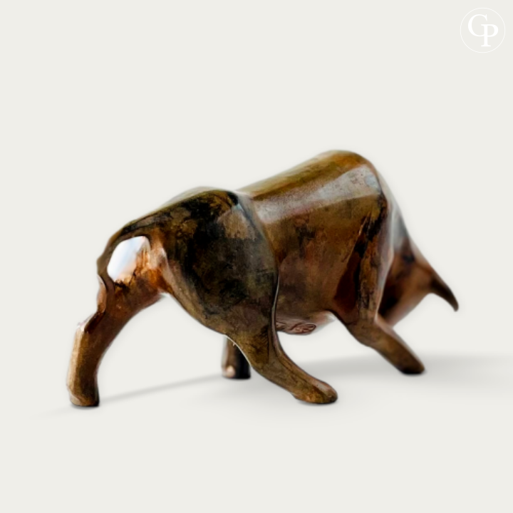 Studio 3/4 rear view of the powerful cubist bull in solid bronze by Pierre Chenet (circa 1970). Dynamic pose highlighting geometric volumes and rich acid patina with warm brown, golden and copper reflections on a clean white background. | Vue studio 3/4 arrière du taureau cubiste en bronze massif par Pierre Chenet (vers 1970). Pose dynamique mettant en valeur les volumes géométriques et la belle patine à l’acide aux reflets bruns profonds, dorés et cuivrés sur fond blanc épuré.