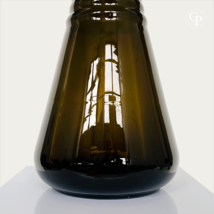 Gros plan sur le corps tronconique et la base circulaire évasée du vase Art Déco, mettant en valeur l'opacité profonde et la silhouette architecturale du verre hyalite fumé marron, Galerie Popincourt | Close-up of the tapered body and flared circular base of the Art Deco vase, highlighting the deep opacity and architectural silhouette of the smoked brown hyalite glass, Galerie Popincourt