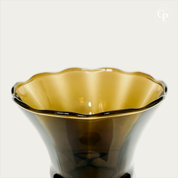 Gros plan horizontal de face mettant en valeur le col évasé en corolle festonnée et la transparence ambrée du verre hyalite fumé sous la lumière, Galerie Popincourt | Horizontal close-up front view highlighting the flared ruffled rim and the amber translucency of the smoked hyalite glass under light, Galerie Popincourt