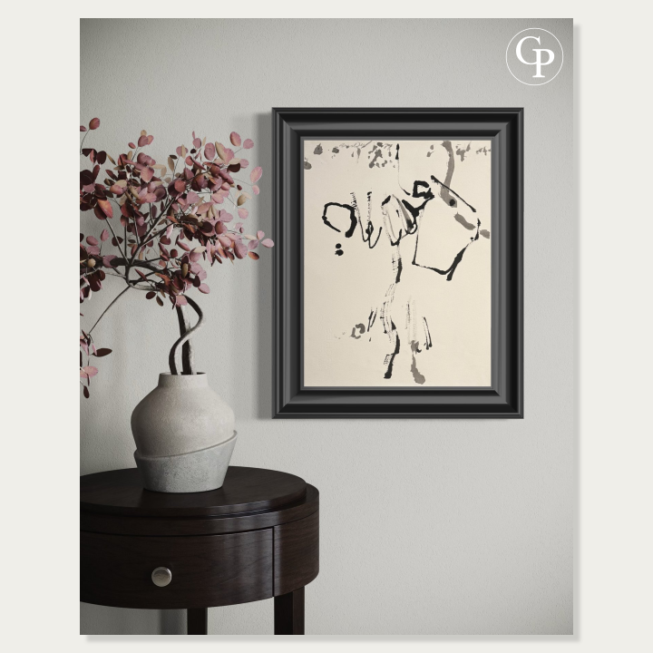 Encre originale Élan Lyrique de Hanna Ben-Dov dans un cadre noir, suspendue sur un mur gris clair au-dessus d'une sellette ronde en bois foncé portant un vase artisanal avec des branches d'eucalyptus rouge. | Framed abstract ink painting Lyrical Impulse by Hanna Ben-Dov on a light grey wall, styled above a dark wood round table with a ceramic vase holding burgundy eucalyptus branches.