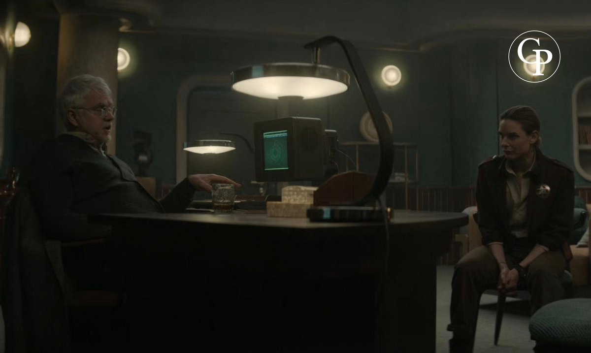 Capture d'écran montrant la lampe de bureau Space Age type FASE MaOf allumée sur un bureau dans une scène de film | Film screenshot showing the illuminated Space Age FASE MaOf desk lamp on an executive desk
