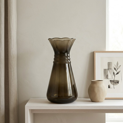 Mise en situation contemporaine et minimaliste du vase Art Déco en verre hyalite fumé marron posé sur une enfilade en bois clair, à côté d'un petit vase en céramique beige et d'un cadre, Galerie Popincourt | Contemporary minimalist lifestyle setting of the Art Deco smoked brown hyalite glass vase on a light wood console table, next to a small beige ceramic vase and a framed artwork, Galerie Popincourt