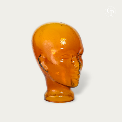 Tête mannequin vintage en verre moulé ambre cognac style Space Age 1970 vue de trois-quarts sur fond neutre | Vintage 1970s Space Age amber cognac molded glass mannequin head three-quarter view isolated on neutral background