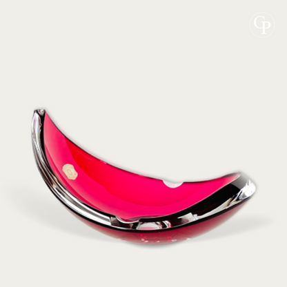 Vue de profil du vide-poche moderniste en cristal rouge rubis de René Delvenne pour Val Saint Lambert, courbe en demi-lune et étiquette d'origine | Side view of the Mid-Century modern ruby red crystal crescent-shaped vide-poche bowl by René Delvenne for Val Saint Lambert, showcasing the elegant curve and original label.