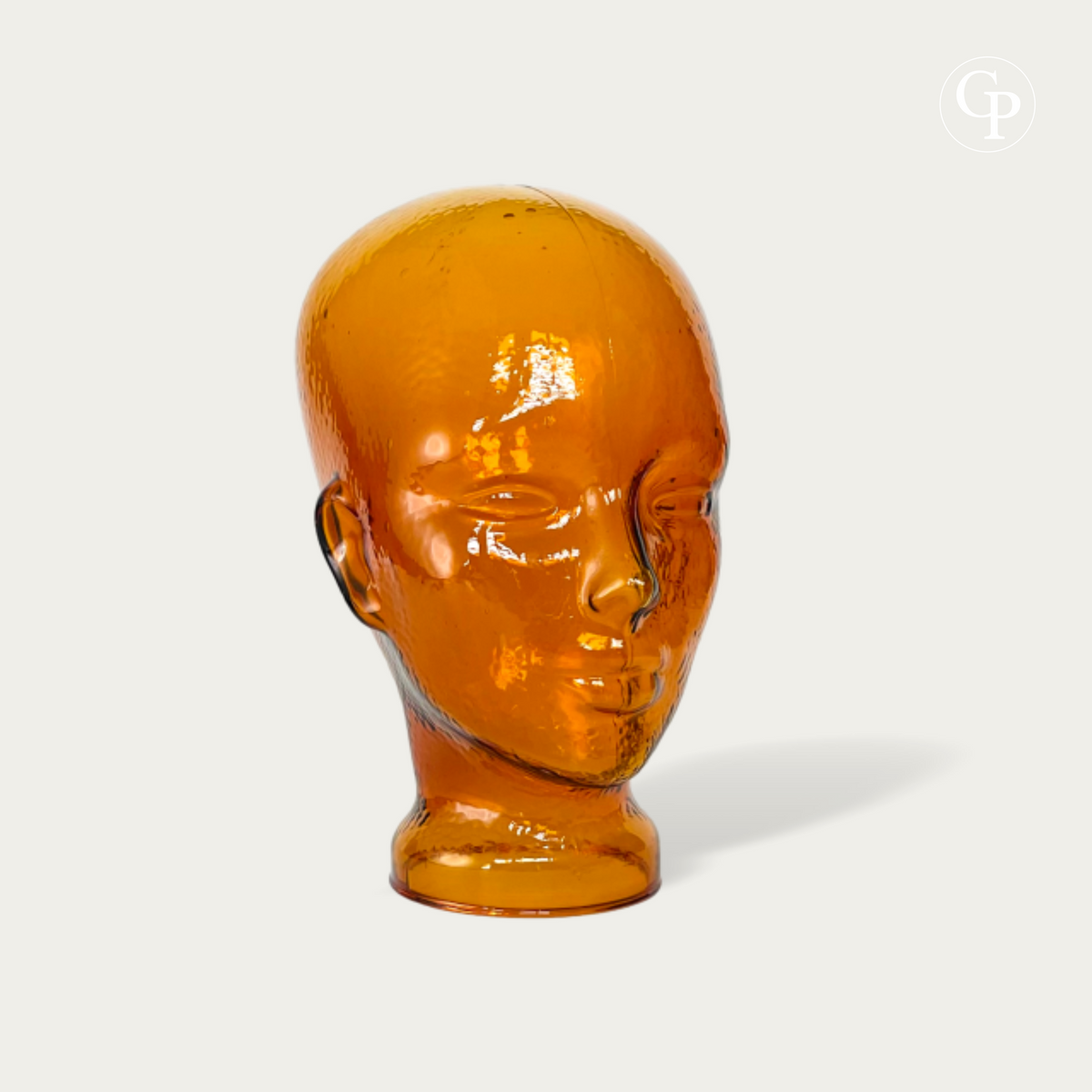 Tête mannequin vintage en verre moulé ambre cognac style Space Age 1970 vue de trois-quarts sur fond neutre | Vintage 1970s Space Age amber cognac molded glass mannequin head three-quarter view isolated on neutral background