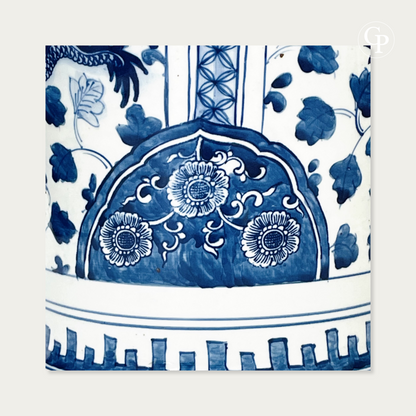 Gros plan sur le motif peint à la main en bleu de cobalt représentant une réserve fleurie de chrysanthèmes et la frise géométrique à la base du vase | Close-up of the hand-painted cobalt blue floral medallion with chrysanthemums and geometric frieze pattern near the base of the vase