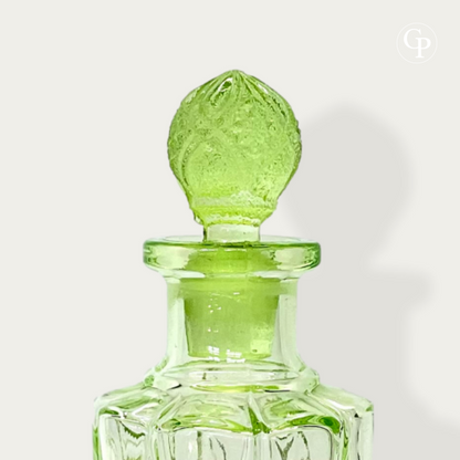 Close-up of the neck and original faceted pineapple stopper on the Val Saint Lambert Ouraline uranium glass perfume bottle, showcasing the glowing green glass, Art Deco circa 1935. | Gros plan sur le col et le bouchon d'origine facetté en forme de pomme de pin du flacon Val Saint Lambert en verre à l'uranium Ouraline, mettant en valeur le verre vert luminescent, Art Déco vers 1935.
