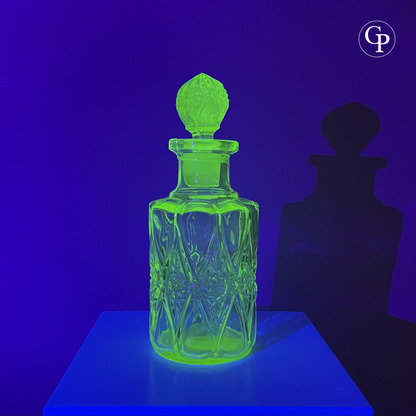 Spectacular view of the Val Saint Lambert Ouraline uranium glass perfume bottle glowing intense neon green under UV light, highlighting its authentic uranium content, Art Deco circa 1935. | Vue spectaculaire du flacon Val Saint Lambert en verre à l'uranium Ouraline illuminé d'un vert néon intense sous lumière UV, mettant en évidence son authentique teneur en uranium, Art Déco vers 1935.