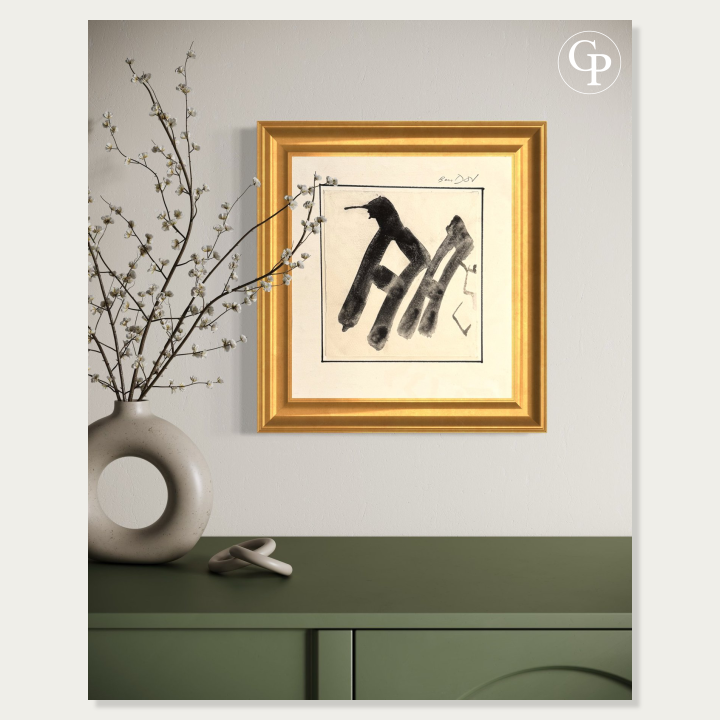 Hanna Ben-Dov minimalist black ink artwork shown in a classic gold frame hanging above a green console table with a modern beige ring vase. | Œuvre à l'encre noire minimaliste de Hanna Ben-Dov présentée dans un cadre doré classique au-dessus d'une console verte avec un vase anneau beige moderne.