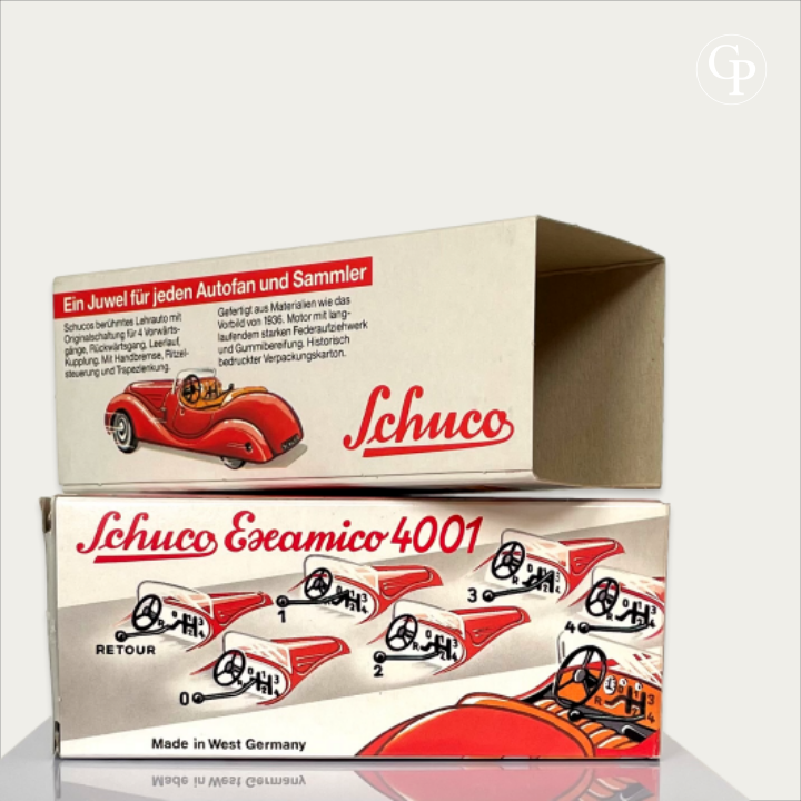 Original vintage packaging and protective sleeve for the Schuco Examico 4001 toy car, showing period illustrations, gear shift instructions, and 'Made in West Germany' marking on a light background. | Boîte d'origine et fourreau protecteur de la voiture miniature Schuco Examico 4001, mettant en valeur les graphismes d'époque, les schémas de passage des vitesses et l'inscription 'Made in West Germany' sur fond clair.